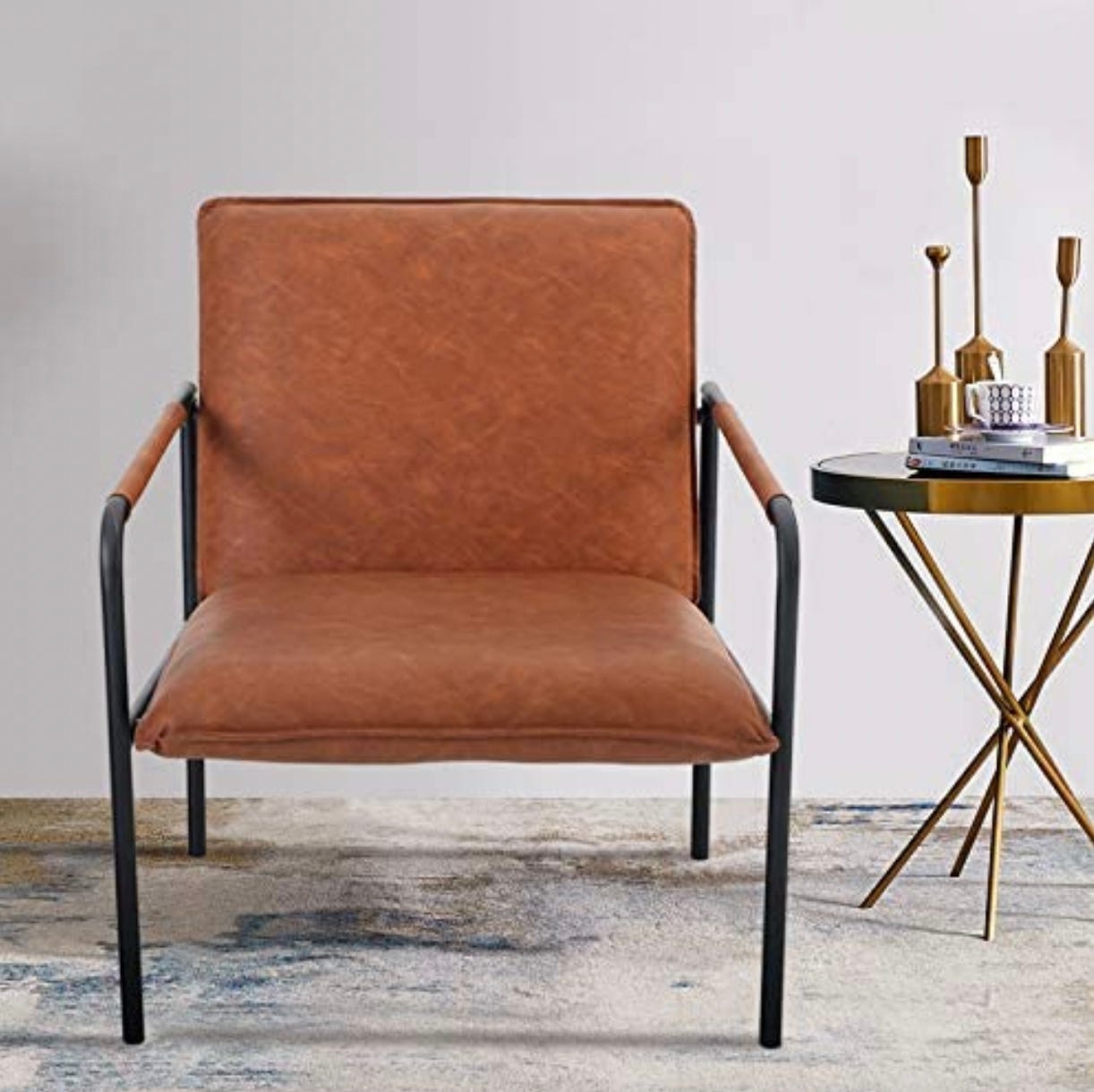 A modern accent chair with a leather-like brown seat and backrest, and black metal armrests which seamlessly extend to form the legs.