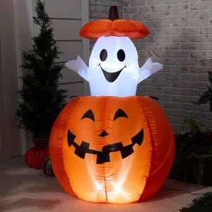 Inflatable Halloween decoration features a smiling ghost inside a carved pumpkin with a jack-o'-lantern face, illuminated for nighttime visibility.