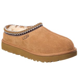 A tan suede slipper with a sheepskin lining, featuring a rubber sole and decorative stitching around the ankle.