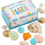 Colorful box of Cheryl’s cookies with designs and text \“You've Been Egged,\“ including chocolate chip, sugar cookies with frosting, and an orange carrot-shaped cookie.