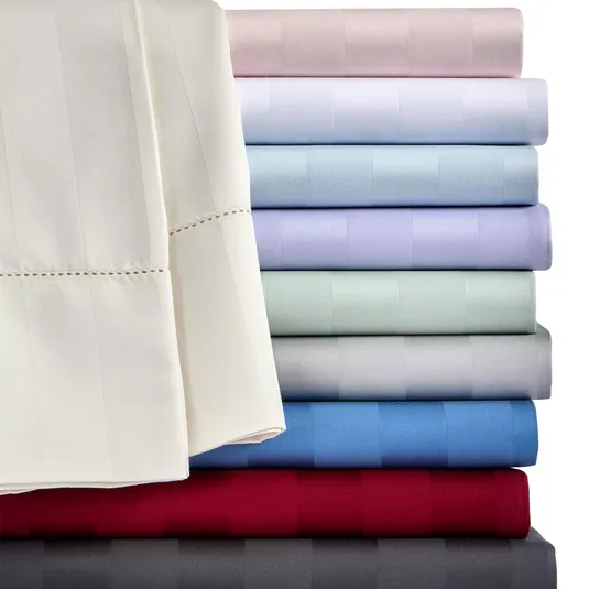 A stack of neatly folded bed sheets in various colors, including white, pink, light blue, lavender, mint green, gray, blue, and red, each featuring a subtle stripe pattern and decorative hemstitching.