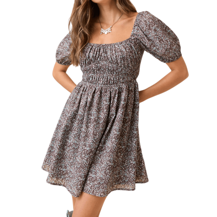 A woman is wearing a floral-patterned, short-sleeve, smocked mini dress with a square neckline.