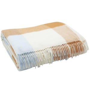 A folded plaid blanket with a checked pattern in white, blue, and tan, featuring fringe on the edges.