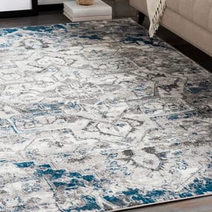 A 5' square area rug features a distressed design with intricate patterns in gray, white, and blue hues, adding a modern and stylish touch to the room's decor.