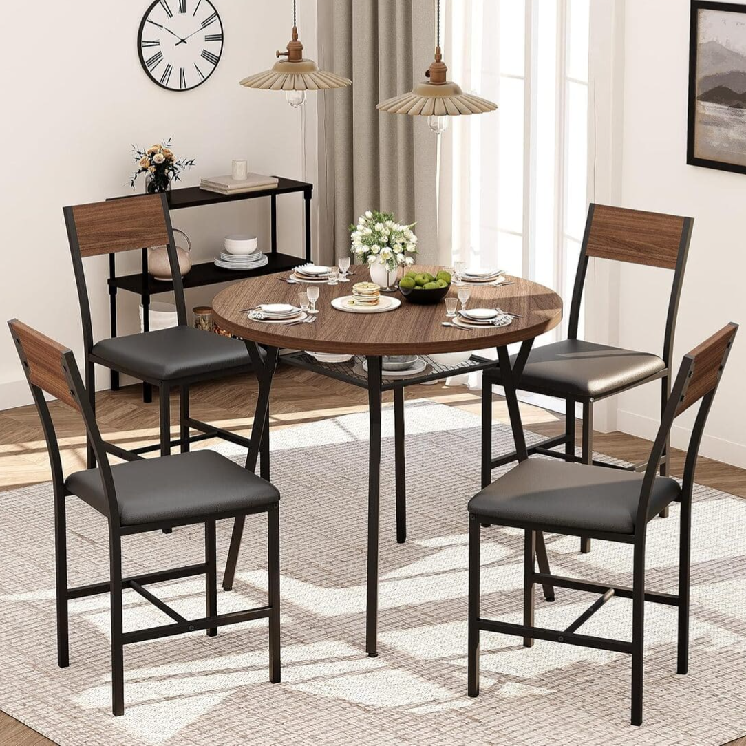 Dining set with a round wooden table and four chairs featuring black seats and wooden backrests, accompanied by tableware, a small serving cart, pendant lights, and a wall clock, all set on a textured rug.