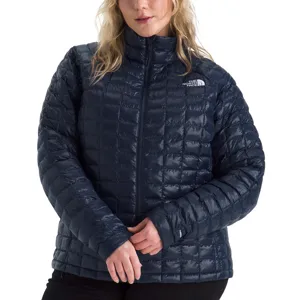 A woman wearing a navy quilted puffer jacket from The North Face, featuring a high collar and front zipper closure.