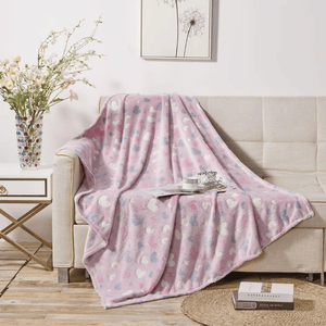 A pink throw blanket with heart and star patterns draped over a couch, with a cup and saucer on top.