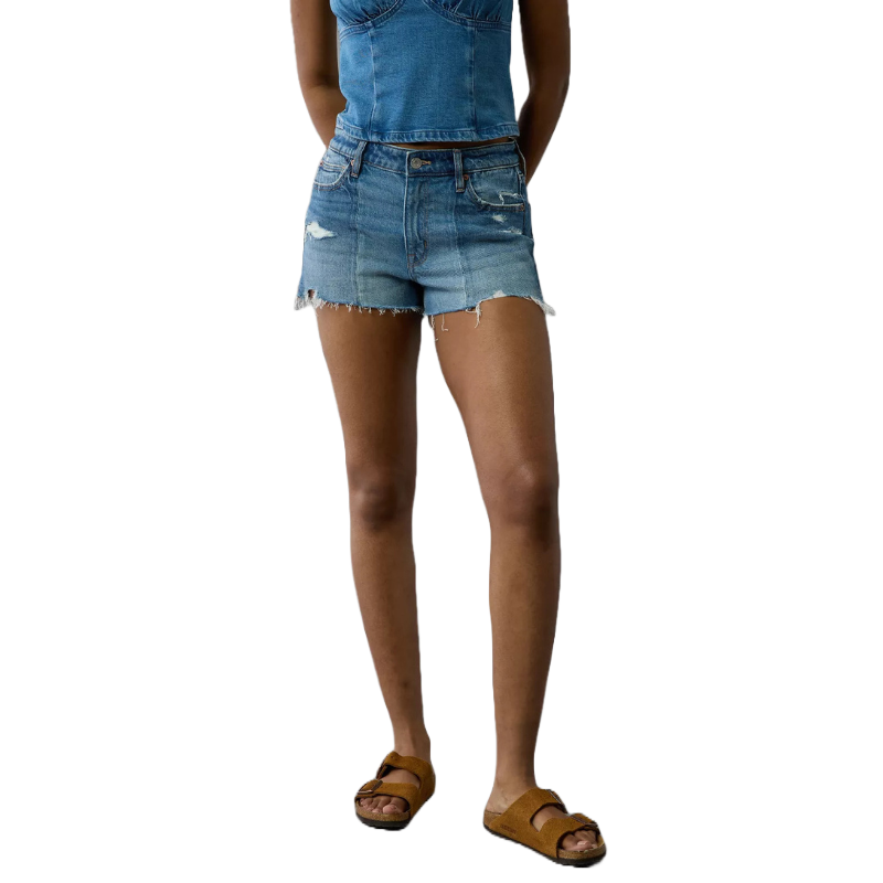 A person is wearing a denim top with matching distressed denim shorts and brown sandals.