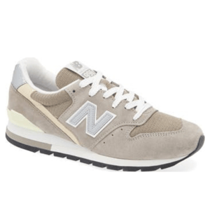 The New Balance 996 V1 Sneaker features a suede and mesh upper in a neutral beige color, with white laces and a grey \“N\“ logo on the side. The shoe has a padded collar for comfort and a rubber outsole for traction.
