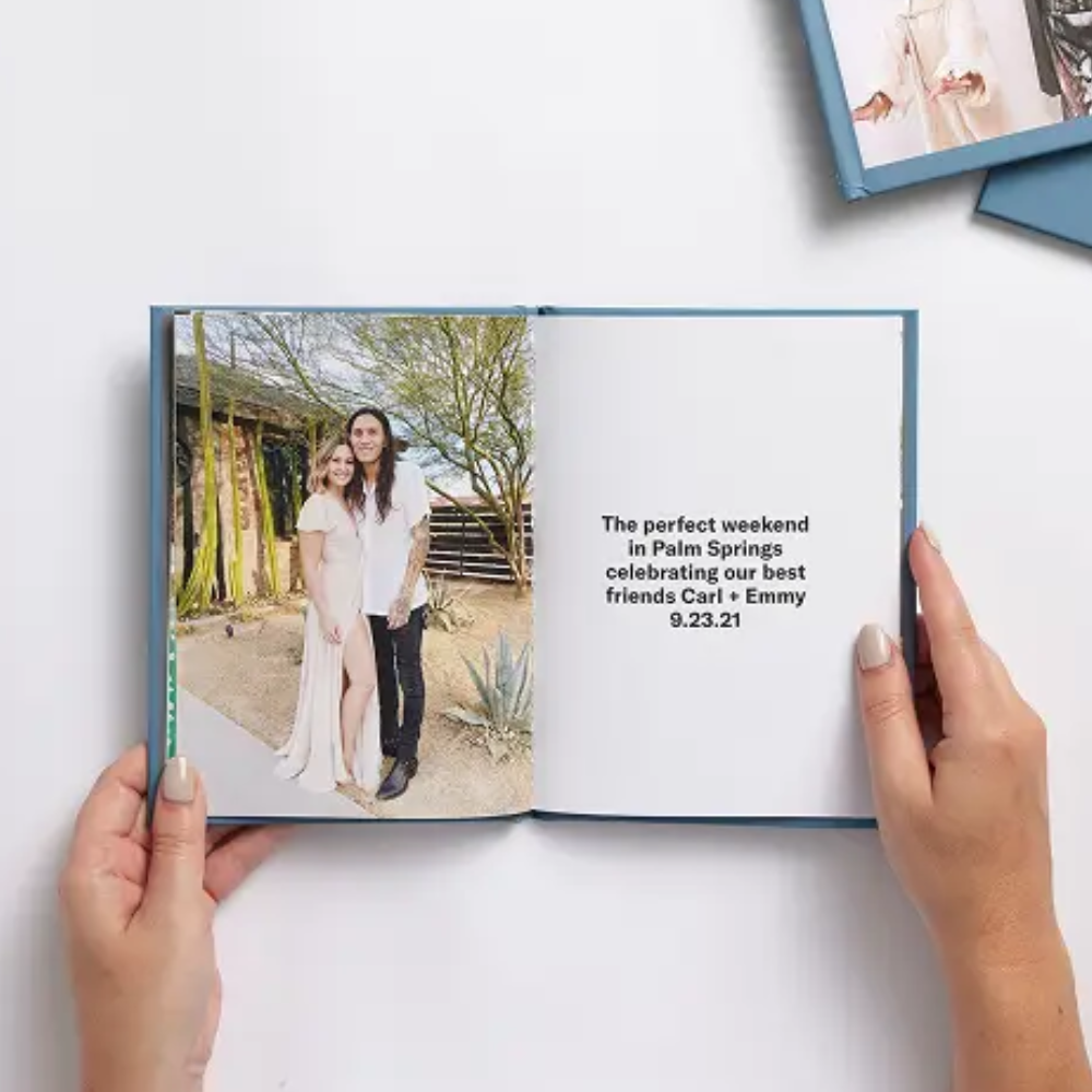 A photo book with a couple's picture on one page and text on the other, mentioning a weekend celebration in Palm Springs for friends Carl and Emmy on September 23, 2021.