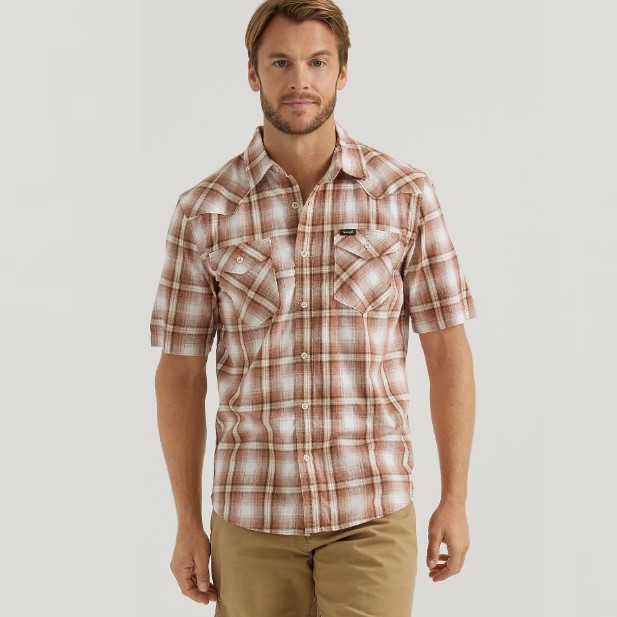 A man is wearing a short-sleeve, plaid button-up shirt and khaki pants.