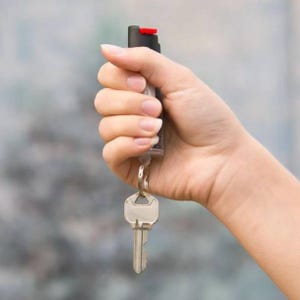 A hand holding a key with an attached car remote control fob.