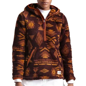 A person wears a fleece pullover hoodie with a geometric tribal pattern in shades of brown and orange, featuring a front kangaroo pocket and partial zip front.