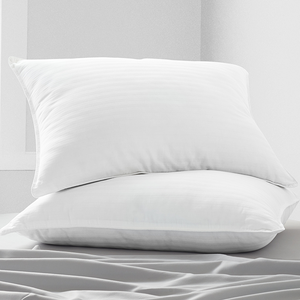 Two white pillows with a subtle striped pattern stacked on a bed with smooth, light gray sheets.
