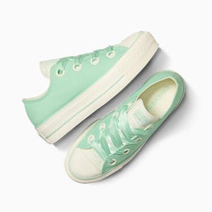 A pair of mint green canvas sneakers with white laces and rubber soles, shown from above.