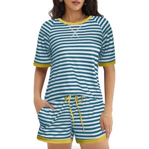 A woman is wearing a striped pajama set featuring a short-sleeved top and shorts in blue and white with yellow accents.