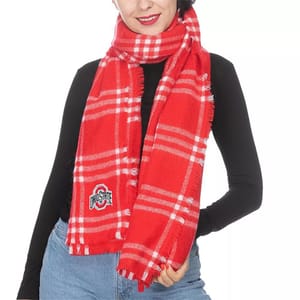 A person wears a red plaid scarf with white stripes, featuring an \“Ohio State\“ logo, paired with a black top and blue jeans.