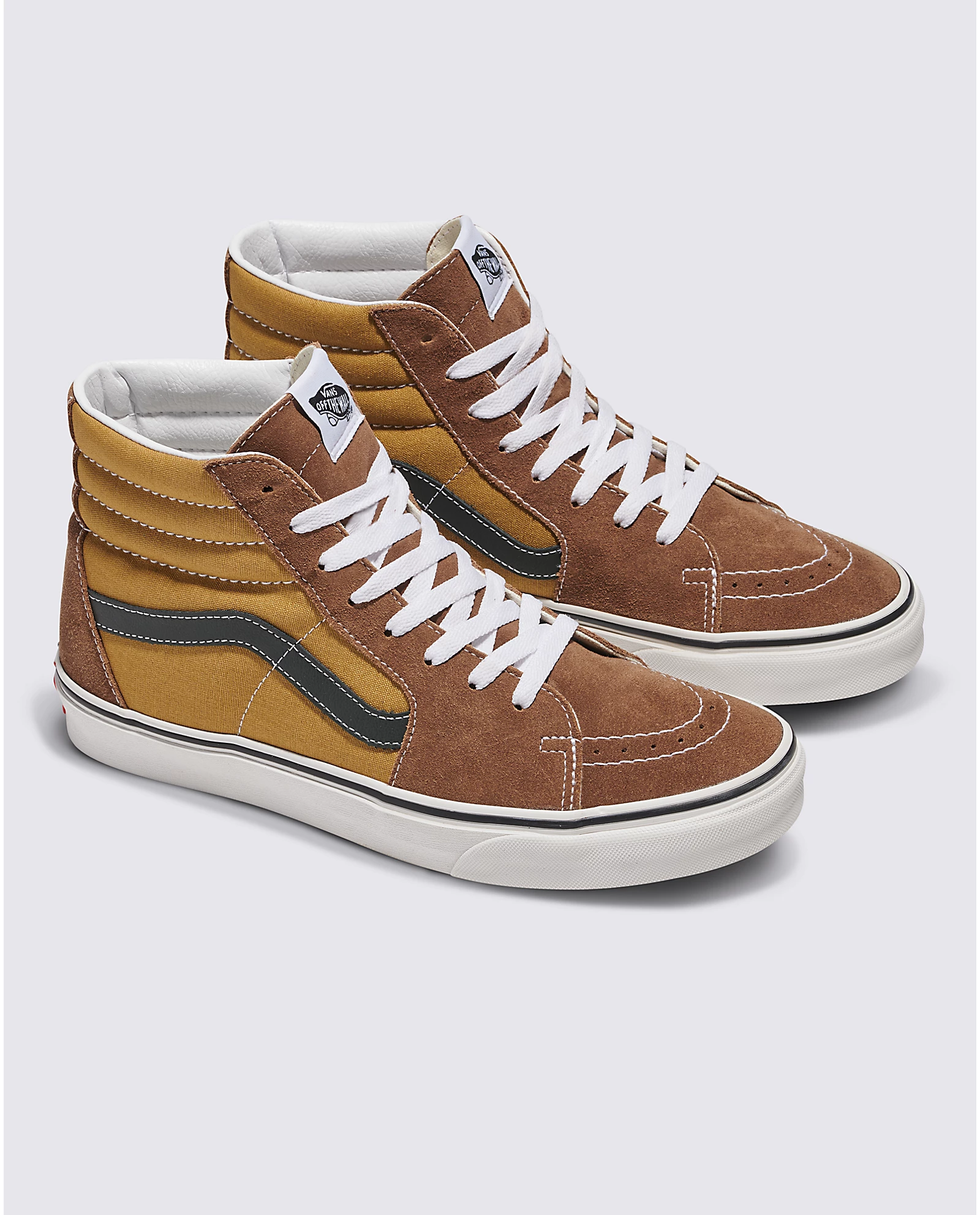 A pair of high-top sneakers with brown, mustard, and dark green panels and white laces.