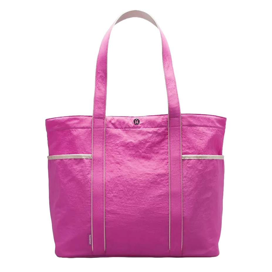 A vibrant pink lululemon Daily Multi-Pocket Tote Bag featuring dual shoulder straps, multiple compartments for organization, and a minimalist logo detail on the front.