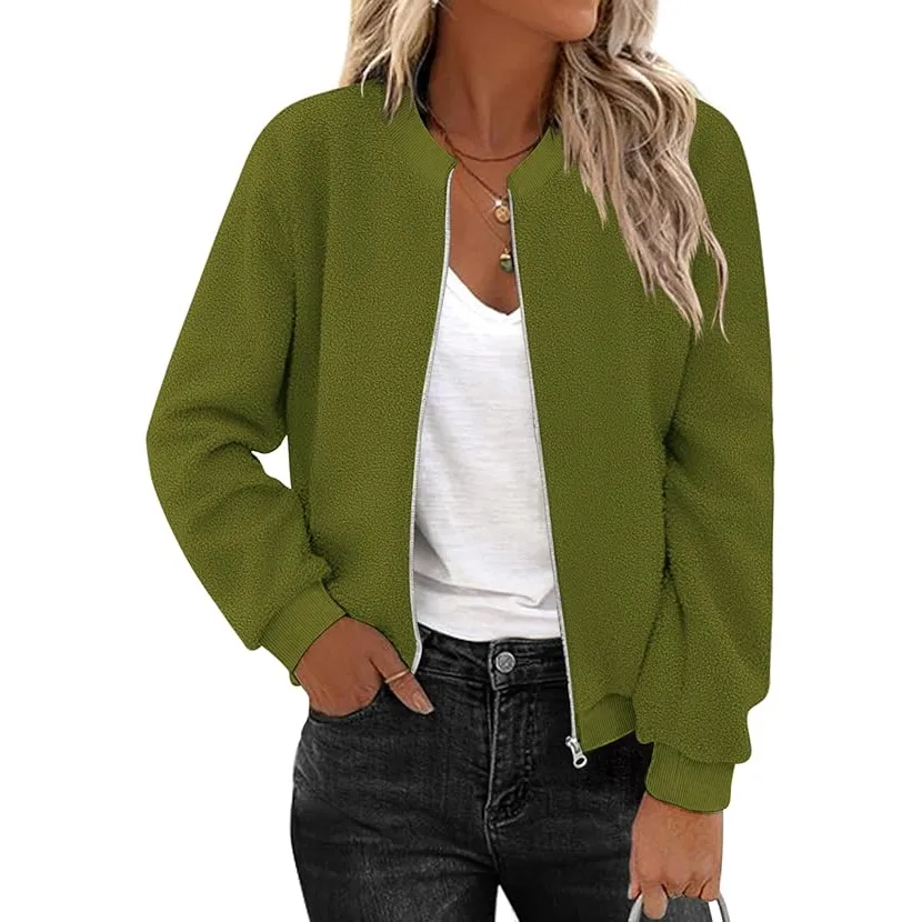 A woman wears an olive green fleece jacket with a zip-up front, ribbed cuffs, and a collar. She pairs it with a white V-neck t-shirt and black jeans, accessorized with a necklace.