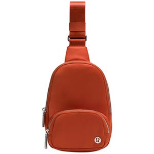 Orange Lululemon sling bag with front zip pocket and adjustable strap.