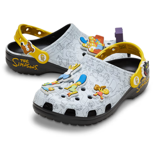 A pair of Crocs featuring \“The Simpsons\“ theme, with yellow straps and character charms on a white backdrop with outlined sketches.