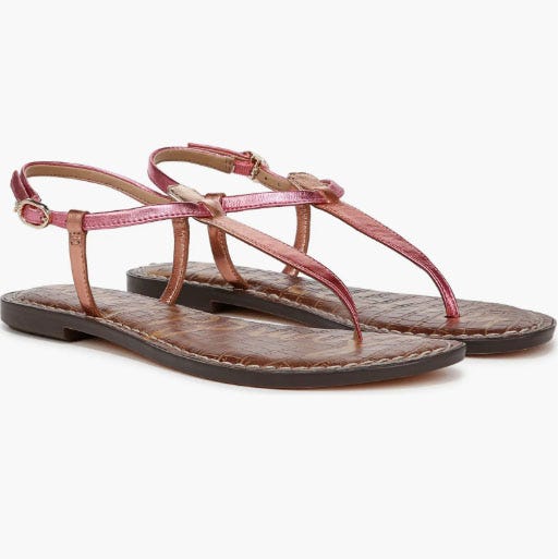 Pink metallic thong sandals with a brown textured flat sole and adjustable ankle straps.