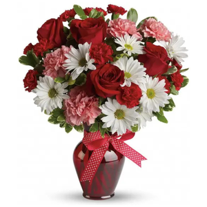 A bouquet featuring red roses, pink carnations, red carnations, and white daisies, arranged in a deep red vase adorned with a polka dot red ribbon.