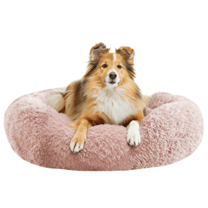A dog is comfortably resting on a plush, round, pink pet bed.
