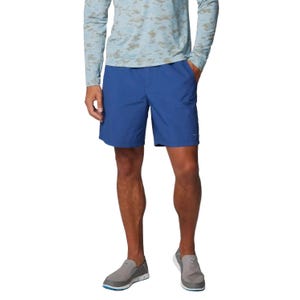 Man wearing blue shorts, a light camouflage long-sleeve shirt, and gray slip-on shoes.