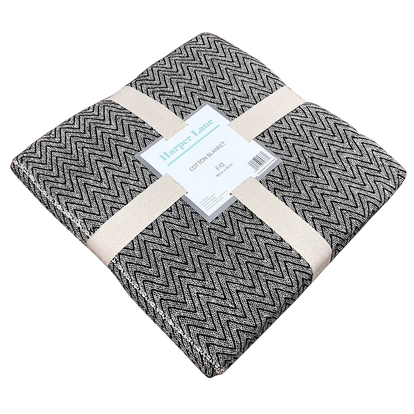 Harper Lane cotton blanket, featuring a black and white zigzag pattern, folded and secured with beige straps.
