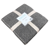 Harper Lane cotton blanket, featuring a black and white zigzag pattern, folded and secured with beige straps.