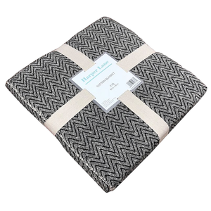Harper Lane cotton blanket, featuring a black and white zigzag pattern, folded and secured with beige straps.