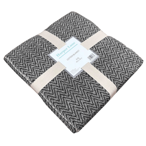 Harper Lane cotton blanket, featuring a black and white zigzag pattern, folded and secured with beige straps.