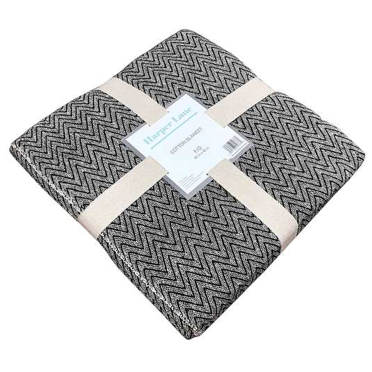 Harper Lane cotton blanket, featuring a black and white zigzag pattern, folded and secured with beige straps.