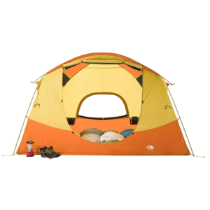 A spacious yellow and orange dome tent with a small entrance, accompanied by a pair of black shoes and a red lantern outside. Inside, there are three visible sleeping bags.