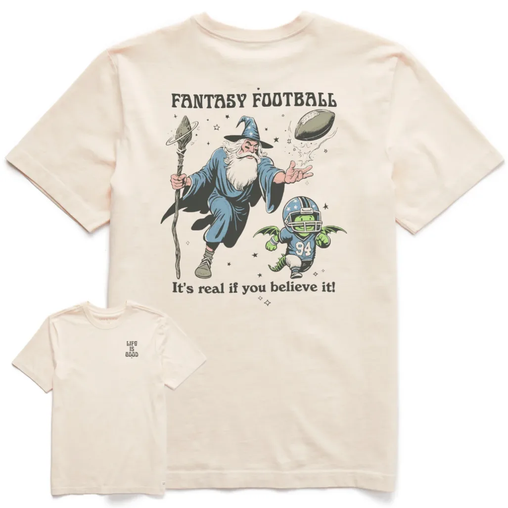 A cream-colored T-shirt featuring a wizard conjuring a flying football with the text \“FANTASY FOOTBALL\“ and \“It's real if you believe it!\“ A small character in football gear with wings is also depicted. The front has \“LIFE IS GOOD\“ printed on the chest.