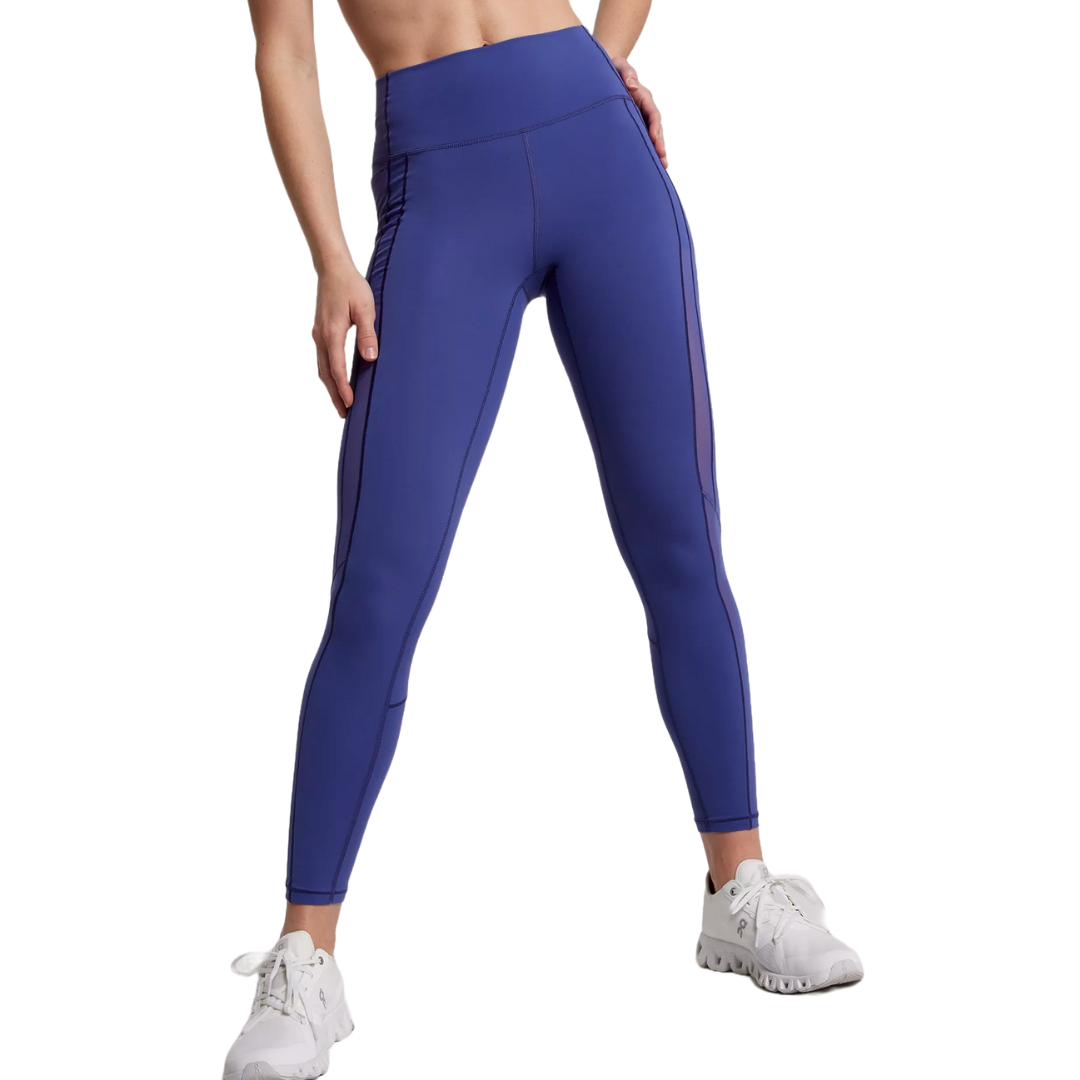High-rise purple leggings with mesh detailing on the sides, designed for athletic wear. Paired with white sneakers, they provide a fitted and stretchy appearance.