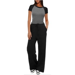 A person is wearing a two-tone fitted short-sleeve top with black sleeves and a gray body, paired with black wide-leg drawstring pants and black-and-white sneakers.