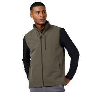 A man is wearing an olive-green zip-up golf vest with black long sleeves underneath. The vest features a high collar and zippered pockets, creating a functional and stylish outerwear piece.