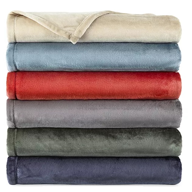 A stack of six neatly folded blankets in various colors: beige, light blue, red, gray, green, and dark blue. They appear soft and plush.