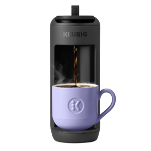 Keurig coffee maker pouring steaming coffee into a lilac mug with the Keurig logo.