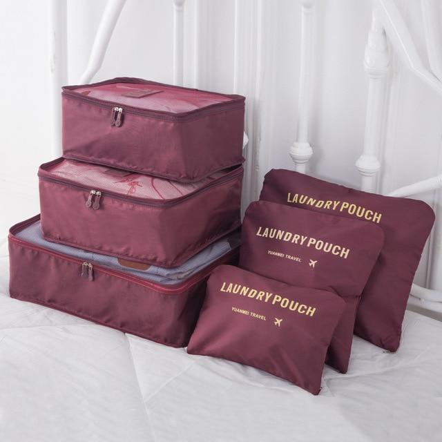 A set of maroon travel packing cubes and pouches, labeled \“LAUNDRY POUCH\“ for organizing clothes while traveling.