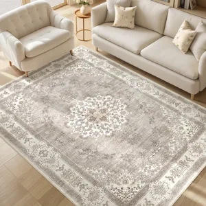 A beige and gray area rug with floral patterns is placed between a cream-colored sofa and an armchair on a light wooden floor.