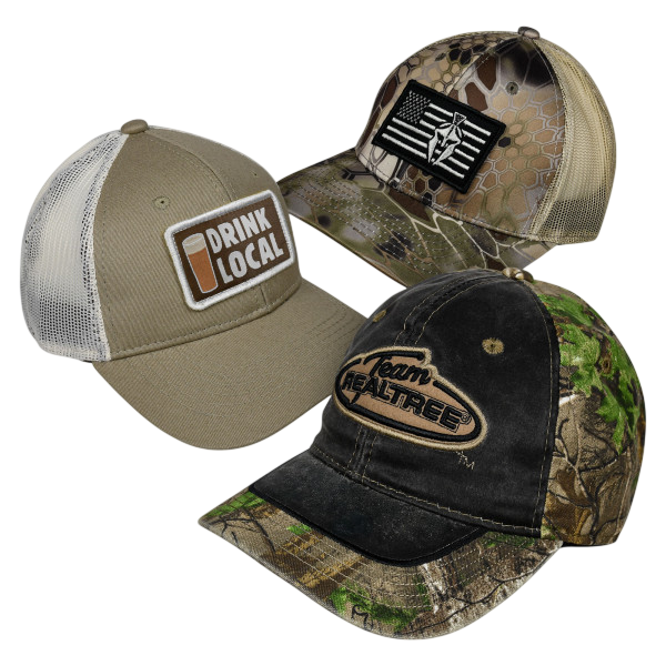 A 3-pack of baseball caps featuring different designs: one with a \“Drink Local\“ patch, another with a camouflage and black flag pattern, and the third with \“Team Realtree\“ on a black and green camo background.
