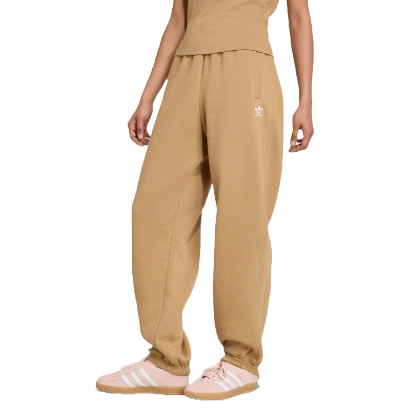 Tan wide-leg sweatpants with an Adidas logo, paired with light pink Adidas sneakers featuring white stripes.