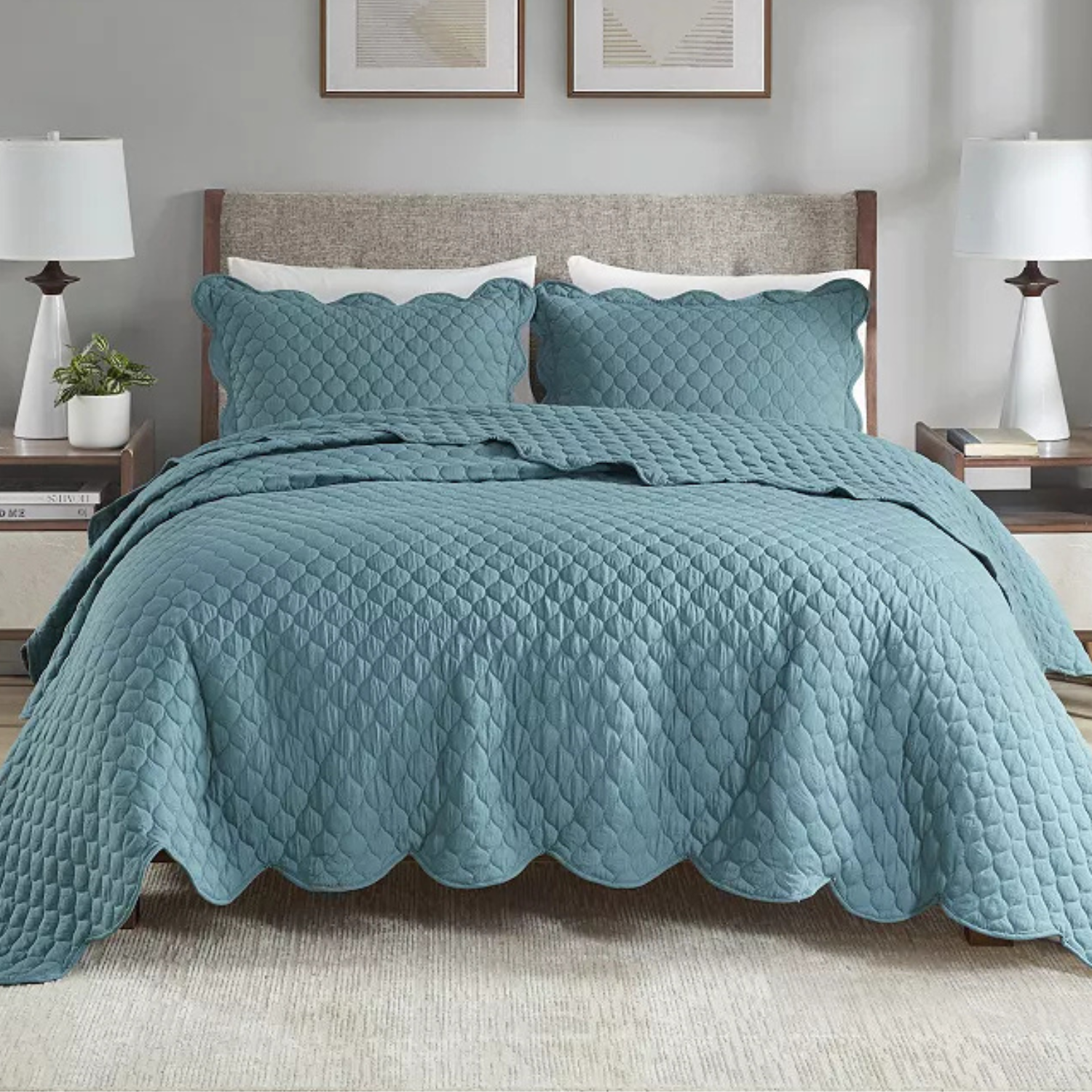 3pc Madison Park King Quilt Set includes a textured teal quilt with a scalloped edge and two matching pillow shams. The set decorates a bed with a clean and modern aesthetic, complemented by neutral bedside lamps and abstract wall art.