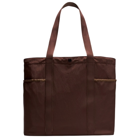 A brown tote bag with a simple design featuring two long handles and exterior side pockets.