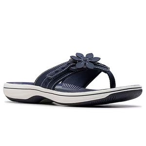 A navy blue flip-flop sandal with white stitching, a flower decoration, and a white sole with a dark tread.