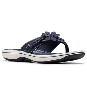 A navy blue flip-flop sandal with white stitching, a flower decoration, and a white sole with a dark tread.